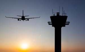 an airplane and air control tower with a sunset background.