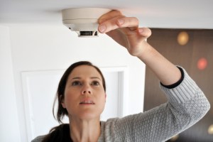 Woman checking smoke detector.