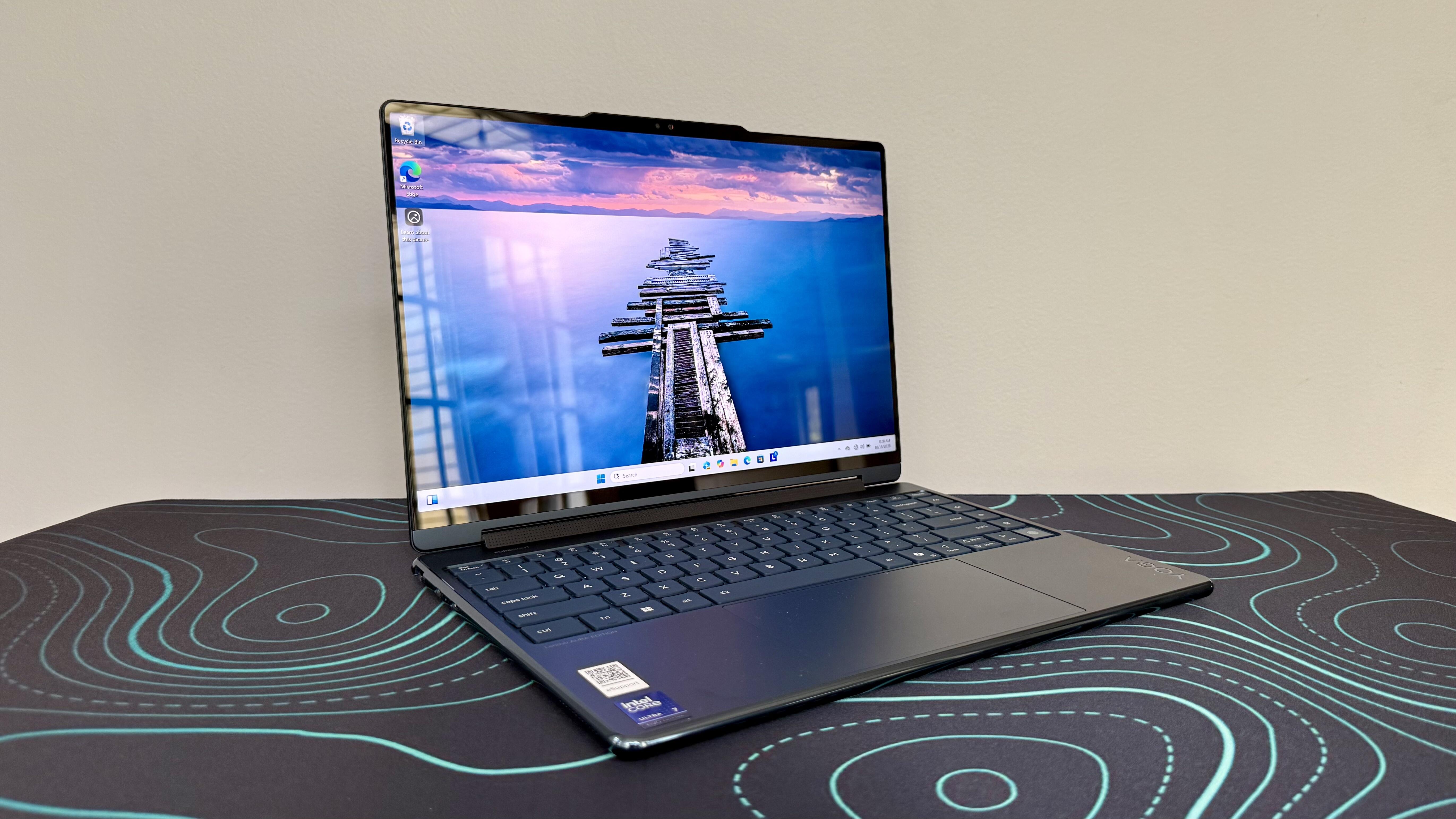 Lenovo Yoga 9i 2-in-1 Aura Edition laptop on a black desk pad with blue lines