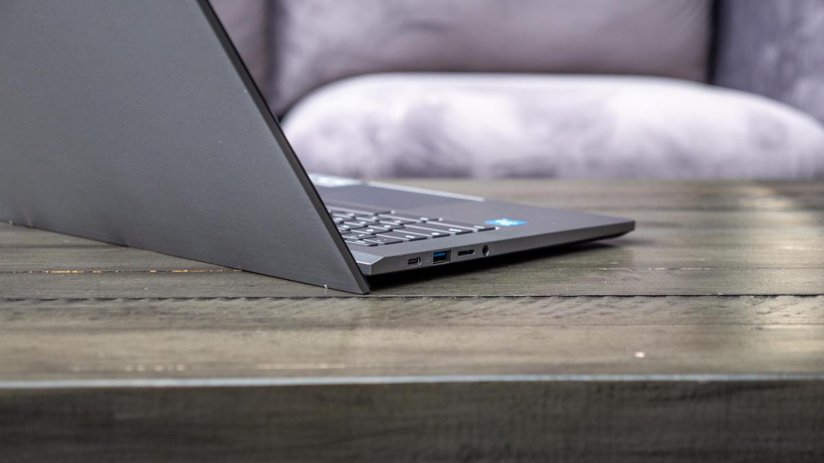 Acer Chromebook Plus 514 open and rear facing right on a wood table in front of a light gray sofa.