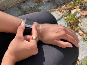 A Whoop 5.0 on a wrist fingers grasping the side indents to get an ECG reading.
